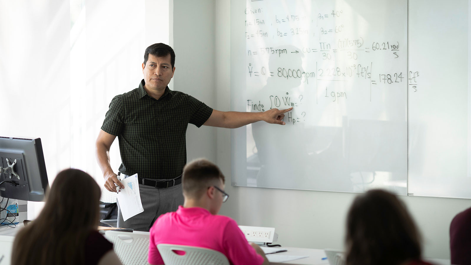 Professor teaches in front of whiteboard.